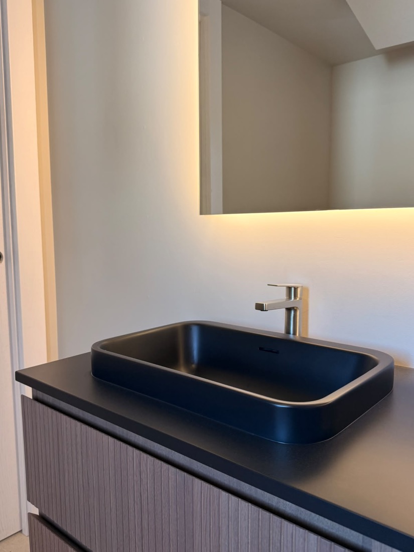 Detalle de lavabo de piedra negra integrado con grifería en acero.