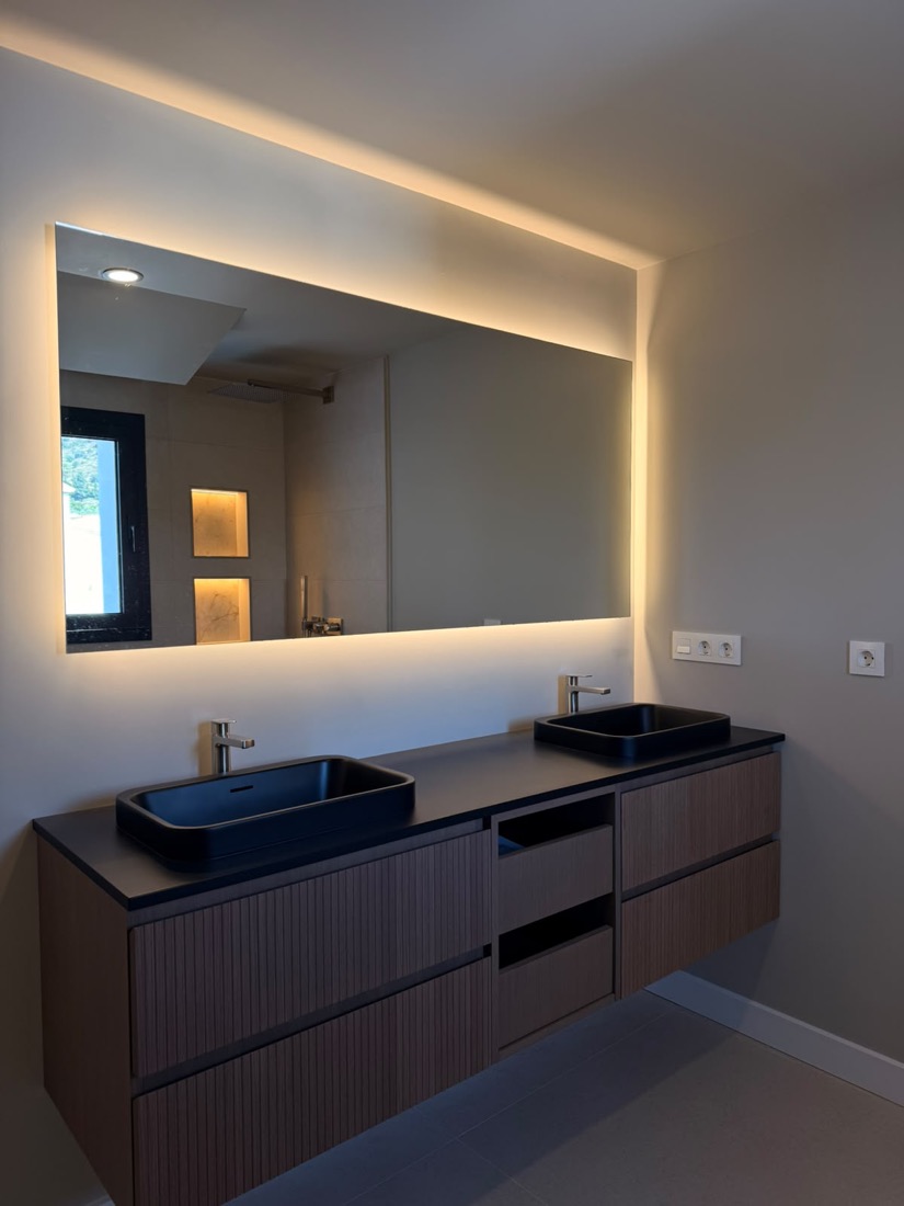 Encimera de baño con mecanismos eléctricos e iluminación integrada en espejo.