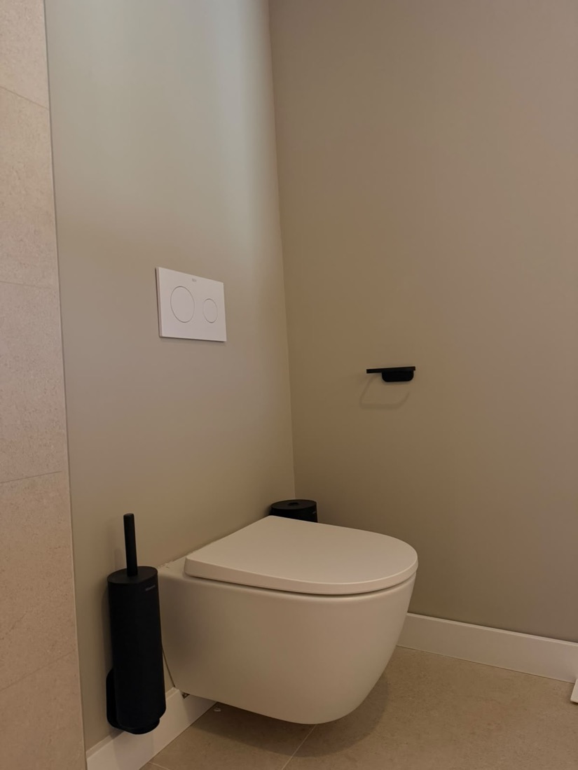 Inodoro suspendido con mecanismo empotrado y accesorios en negro mate.